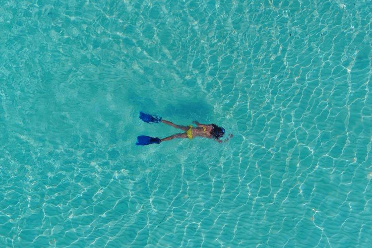Wayfarers Atlas Luxury Family Surf Resort aerial view of a women snorkelling at Soneva Jani