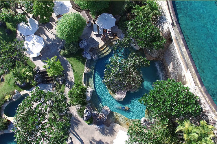 Aerial shot of Four Seasons Jimbaran Bay pools and lush tropical landscape a Bali surf resort in Indonesia